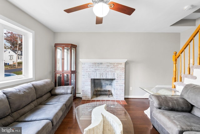 living room with a fireplace, ceiling fan, baseboard heating, and dark wood-type flooring