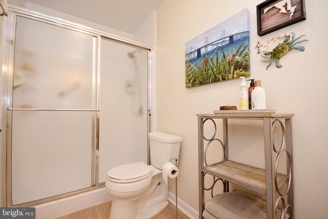 bathroom with a shower with door, hardwood / wood-style floors, and toilet