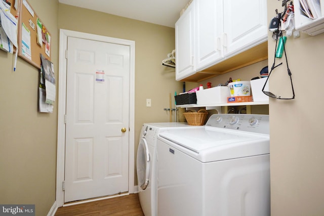 laundry room with separate washer and dryer, cabinets, and hardwood / wood-style flooring