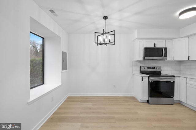 kitchen featuring decorative backsplash, stainless steel appliances, decorative light fixtures, a notable chandelier, and white cabinetry