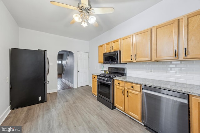 kitchen with ceiling fan, stainless steel appliances, light stone counters, backsplash, and light hardwood / wood-style floors