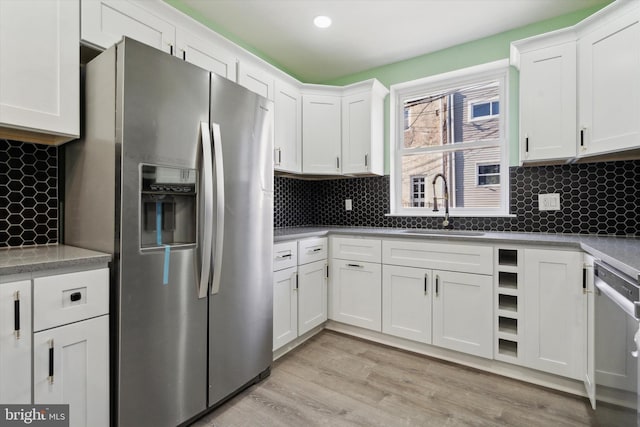 kitchen featuring appliances with stainless steel finishes, tasteful backsplash, sink, light hardwood / wood-style flooring, and white cabinets