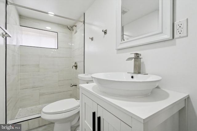 bathroom featuring a tile shower, vanity, and toilet