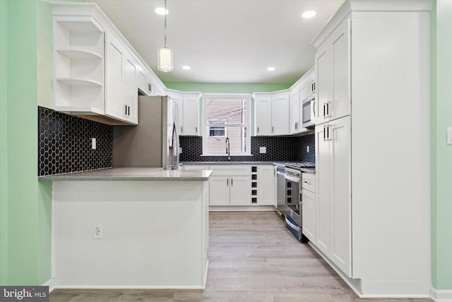 kitchen featuring decorative backsplash, appliances with stainless steel finishes, light wood-type flooring, pendant lighting, and white cabinets