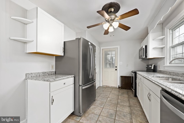 kitchen featuring appliances with stainless steel finishes, light stone counters, ceiling fan, sink, and white cabinets