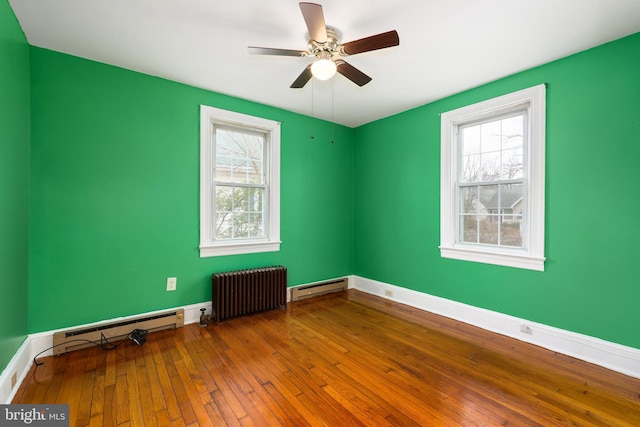 spare room featuring hardwood / wood-style floors, ceiling fan, radiator heating unit, and baseboard heating