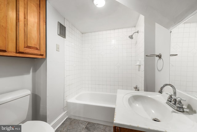 full bathroom with tile patterned floors, vanity, tiled shower / bath, and toilet