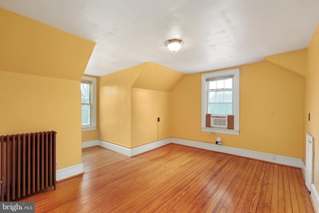 bonus room with cooling unit, hardwood / wood-style flooring, radiator, and lofted ceiling