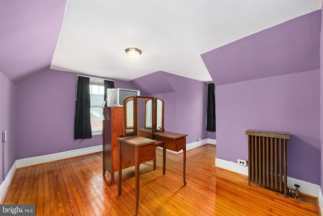 living area featuring radiator heating unit, light wood-type flooring, and lofted ceiling