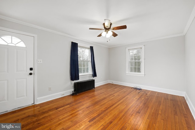 entryway with hardwood / wood-style flooring, ceiling fan, ornamental molding, and radiator