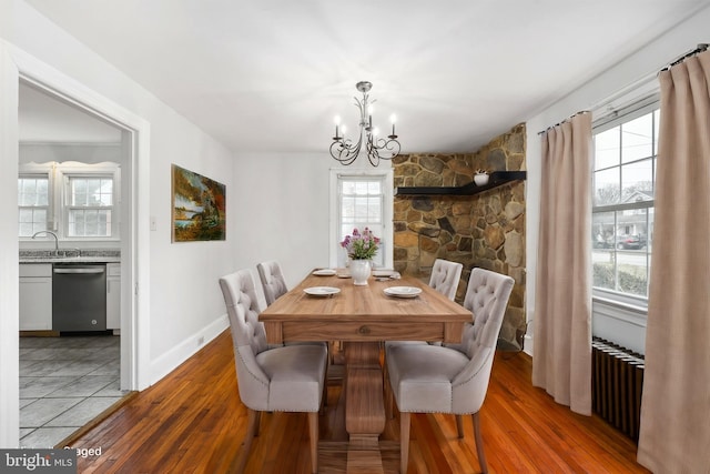 dining area featuring a chandelier, light wood-type flooring, radiator, and sink