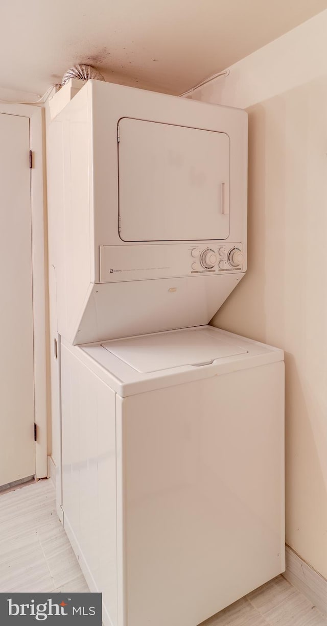 clothes washing area with stacked washing maching and dryer