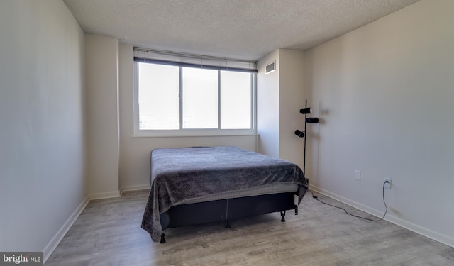 bedroom featuring a textured ceiling and light hardwood / wood-style flooring