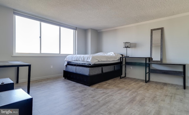 bedroom with crown molding, light hardwood / wood-style floors, and a textured ceiling