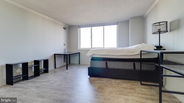 bedroom featuring a textured ceiling, light wood-type flooring, and ornamental molding