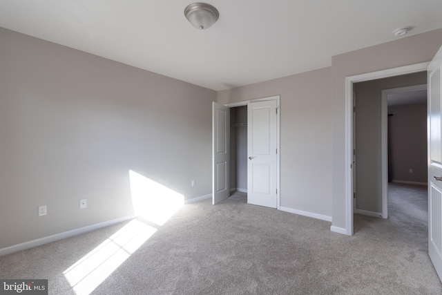 unfurnished bedroom with a closet and light colored carpet