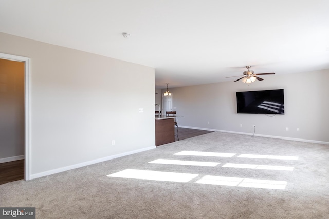 unfurnished living room featuring carpet and ceiling fan with notable chandelier