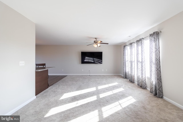 unfurnished living room featuring ceiling fan and light colored carpet