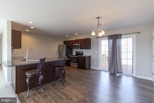 kitchen featuring pendant lighting, sink, appliances with stainless steel finishes, dark hardwood / wood-style flooring, and a chandelier