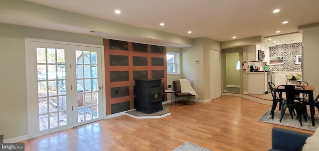 interior space with light hardwood / wood-style floors, a wood stove, and french doors