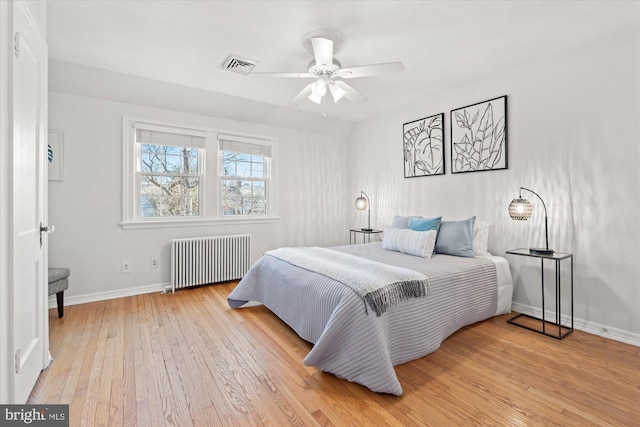 bedroom featuring radiator heating unit, ceiling fan, and light hardwood / wood-style floors