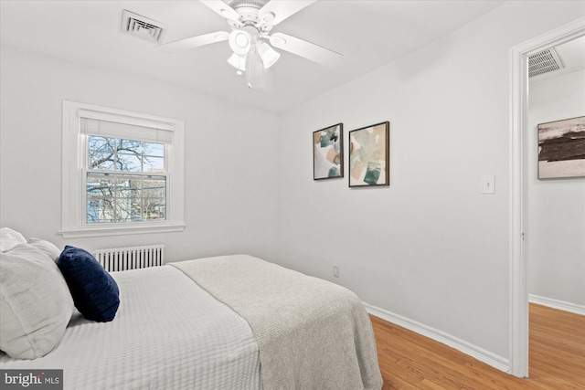 bedroom featuring light hardwood / wood-style flooring, radiator heating unit, and ceiling fan