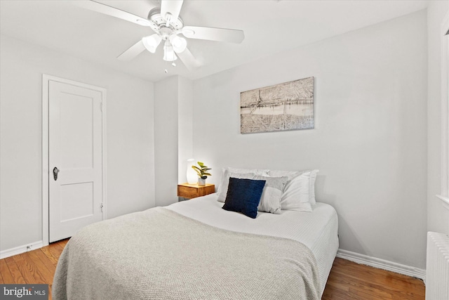 bedroom featuring ceiling fan, radiator heating unit, and wood-type flooring