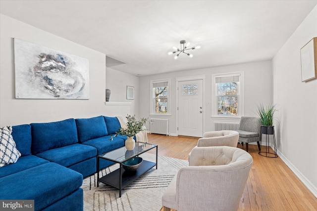 living room with an inviting chandelier, radiator heating unit, and wood-type flooring