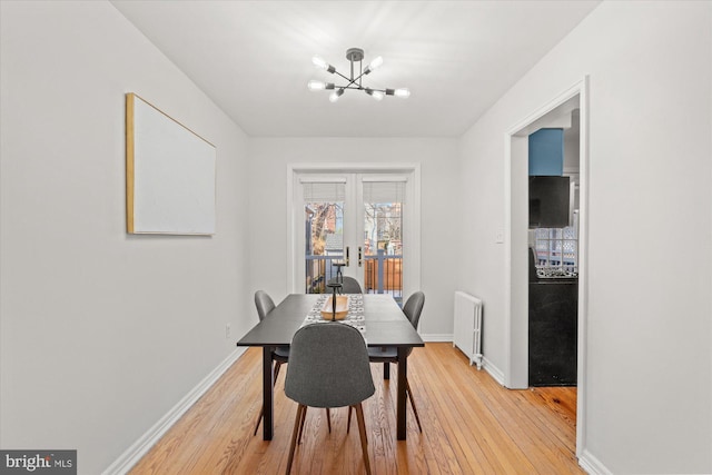 dining space with french doors, radiator, hardwood / wood-style floors, and a notable chandelier