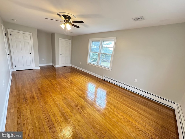 empty room with ceiling fan, a baseboard heating unit, and light hardwood / wood-style flooring