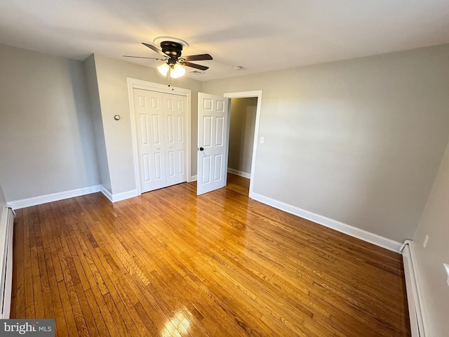 unfurnished bedroom featuring light wood-type flooring, a closet, ceiling fan, and a baseboard heating unit