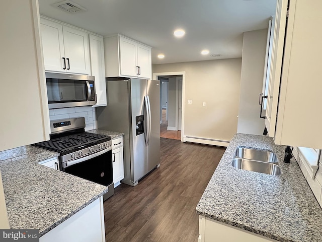 kitchen with dark wood-type flooring, a baseboard heating unit, sink, appliances with stainless steel finishes, and white cabinetry