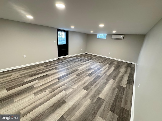 basement featuring a wall unit AC and hardwood / wood-style flooring