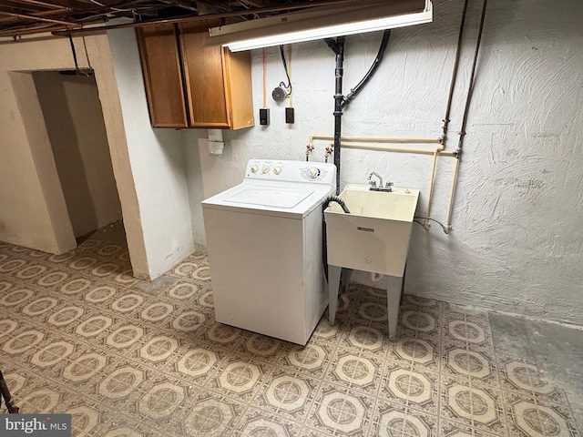 clothes washing area featuring washer / clothes dryer, sink, and cabinets