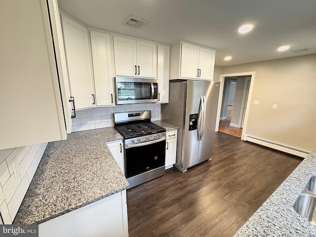 kitchen with dark wood-type flooring, white cabinets, light stone countertops, baseboard heating, and appliances with stainless steel finishes