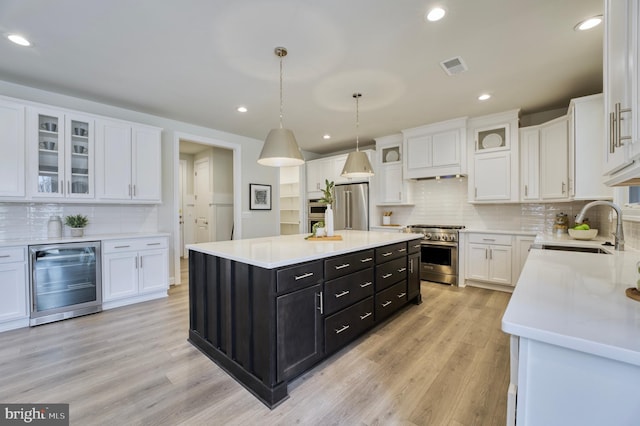 kitchen featuring white cabinetry, a center island, beverage cooler, and premium appliances