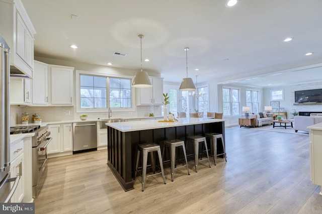 kitchen with appliances with stainless steel finishes, a center island, white cabinetry, and pendant lighting