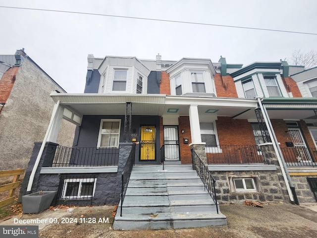 townhome / multi-family property with brick siding and a porch