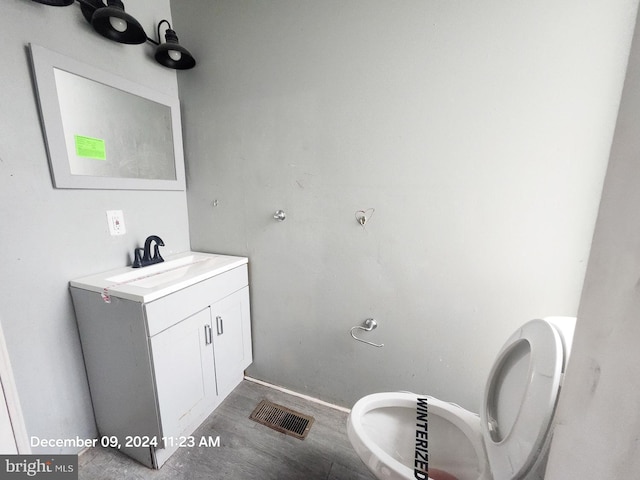 bathroom with hardwood / wood-style floors, vanity, and toilet