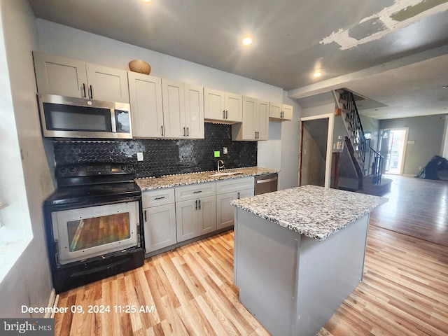 kitchen with backsplash, light stone countertops, light hardwood / wood-style flooring, and stainless steel appliances