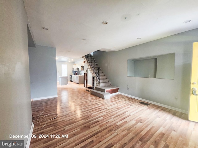 unfurnished room with baseboards, visible vents, light wood finished floors, and stairs