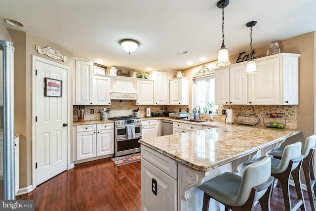 kitchen featuring white cabinetry, dark hardwood / wood-style flooring, kitchen peninsula, pendant lighting, and appliances with stainless steel finishes