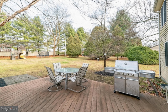 wooden deck with a playground, a grill, a trampoline, and a yard