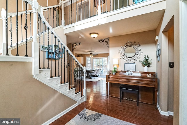 foyer entrance with hardwood / wood-style floors, ceiling fan, and a high ceiling