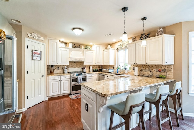 kitchen featuring white cabinets, kitchen peninsula, stainless steel appliances, and hanging light fixtures