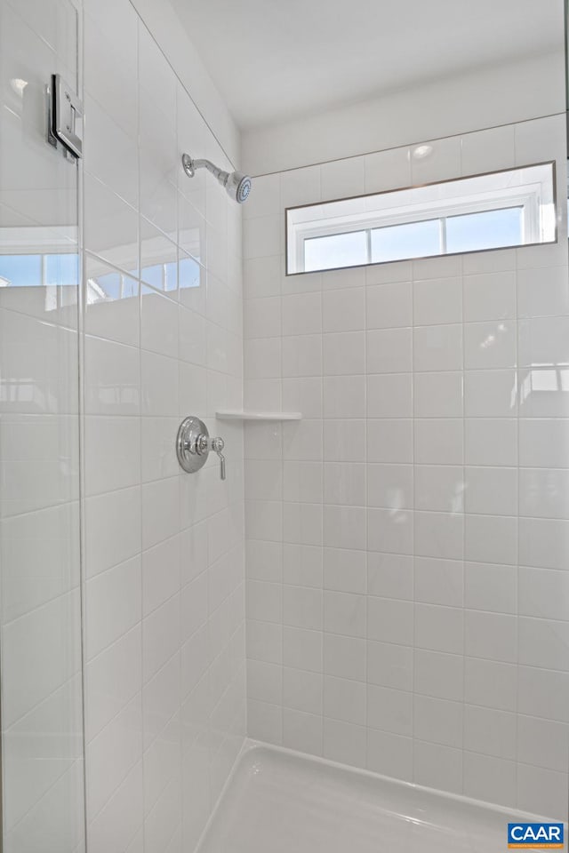 bathroom with a tile shower and a healthy amount of sunlight