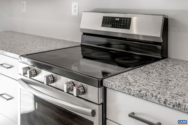 interior space featuring decorative backsplash, light stone counters, white cabinetry, and stainless steel range oven