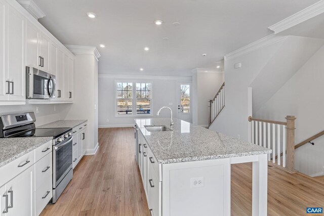 kitchen featuring a kitchen island with sink, sink, light hardwood / wood-style floors, white cabinetry, and stainless steel appliances