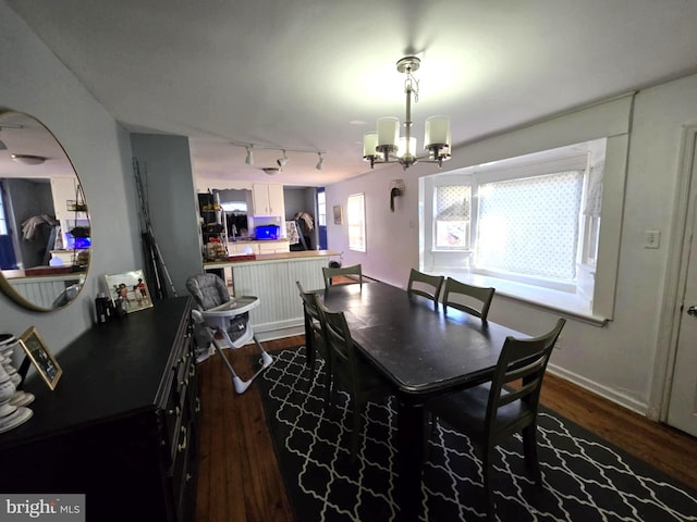 dining space featuring dark hardwood / wood-style flooring, rail lighting, and an inviting chandelier