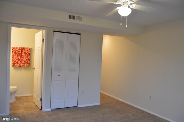 unfurnished bedroom featuring ensuite bathroom, a closet, ceiling fan, and light carpet